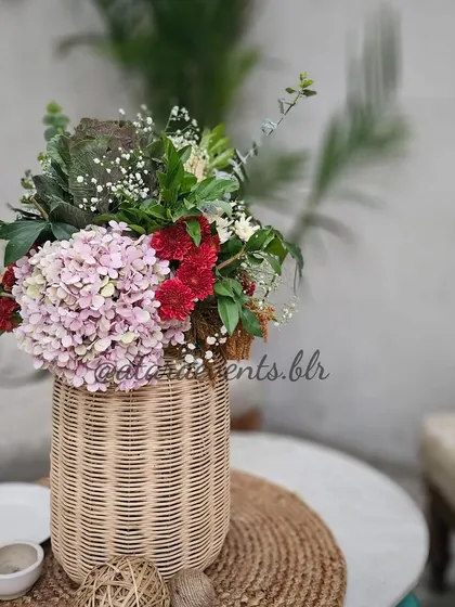 A close-up of a floral arrangement in a woven vase from a boho-themed 30th birthday. The mix of pink hydrangeas and other rustic flowers adds a soft and romantic touch to the decor.