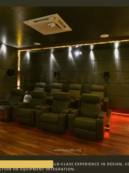 This view shows the full seating arrangement in a modern entertainment lounge. The tiered leather recliners provide an authentic cinema experience, while the wood flooring adds warmth to the space.