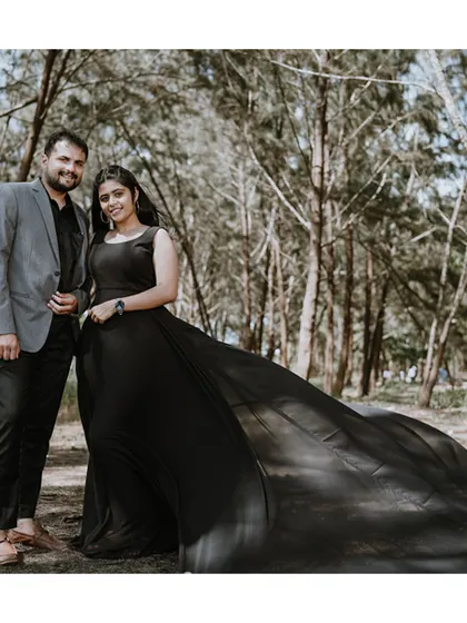 A dramatic and romantic portrait in a wooded area in Goa, with the bride's long black trail dress spread out behind her, creating a stunning visual.