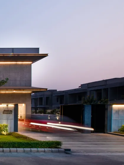 Another view of the entrance at dusk, showcasing the clean lines of the gate and boundary wall, which are integrated into the overall architectural concept.