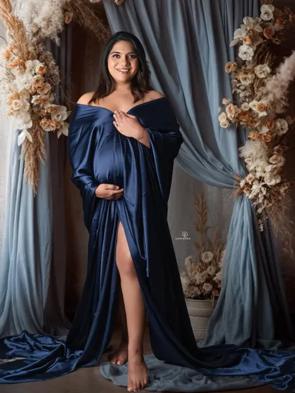 This mom-to-be looks absolutely stunning in a deep blue satin gown. The floral and pampas grass arrangement adds a touch of boho chic to this elegant studio maternity portrait.