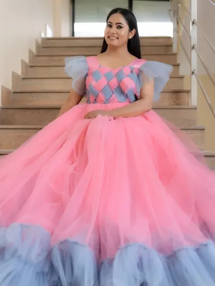 A beautiful full shot of the pink and grey ball gown, showcasing the contrasting ruffles at the hem and the expansive skirt, perfect for a princess-themed shoot.