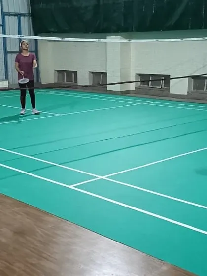 A player stands ready on the badminton court. The clean lines and professional setup of our indoor facility are visible here.