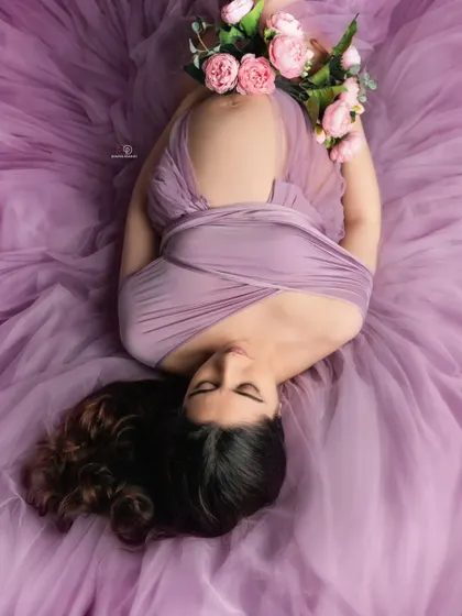 A beautiful overhead shot on a bed of lavender tulle, holding a bouquet of flowers. This creative setup combines a relaxed pose with an artistic, dreamy feel.