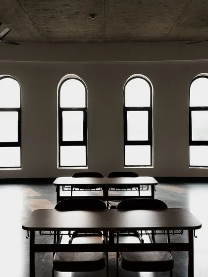 An empty classroom at Mount Carmel, where the architectural language of arched windows and exposed concrete ceilings creates a calm and focused learning environment. The design prioritizes natural light and a sense of spaciousness.