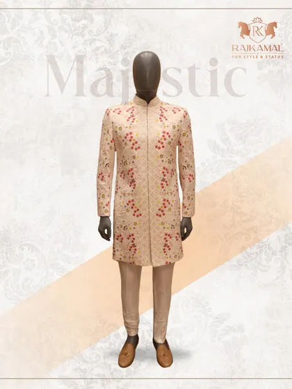 This majestic cream sherwani features delicate red floral embroidery, offering a subtle touch of color. It's a sophisticated choice for the modern groom, shown here on a mannequin to highlight its perfect structure.