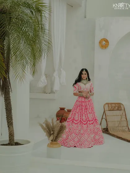 A full-length portrait of the bride in a modern, minimalist setting. The contrast between the vibrant outfit and the white background makes the image pop.