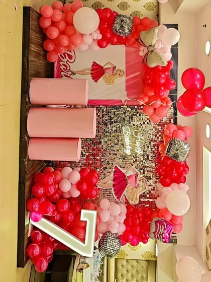 A glamorous Barbie-themed 7th birthday party. This setup features a silver shimmer wall, pink balloon arrangements, Barbie cutouts, and a light-up number '7'.