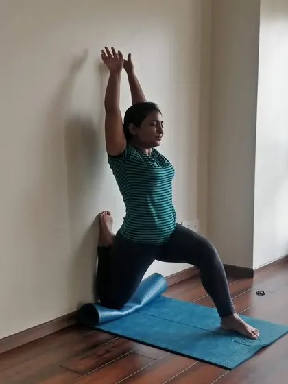 A supported low lunge against the wall helps to deepen the stretch in the quadriceps and psoas muscles.