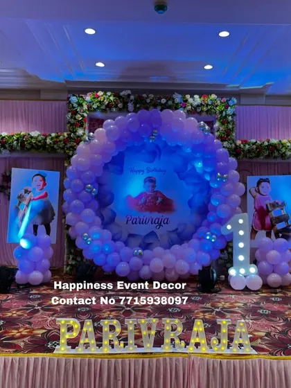 A princess-themed first birthday stage with a central balloon ring and personalized photo posters. The child's name is displayed in front with marquee letters.