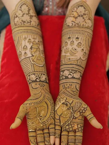 A beautiful bridal design with figures of a musician and a dancer. The arms are decorated with hanging jhumkas and other traditional patterns.