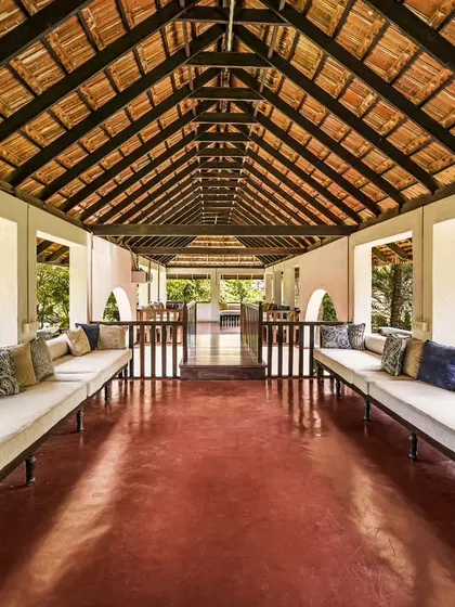 A comfortable lounge area in an open-air veranda, with long cushioned benches overlooking the gardens. It's a perfect place for guests to gather, talk, or simply relax.