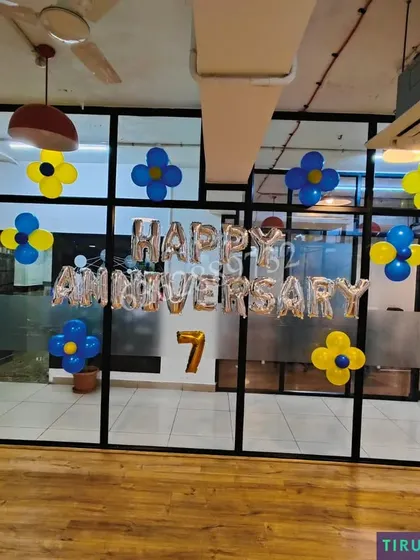 Celebrating a 7th company anniversary with 'Happy Anniversary' foil balloons and simple balloon clusters in the office common area.