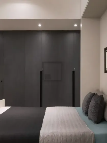 For a more minimalist and modern aesthetic, this bedroom features a sleek, handleless wardrobe in a matte dark grey finish. The clean lines and seamless look help create a calm and uncluttered atmosphere.