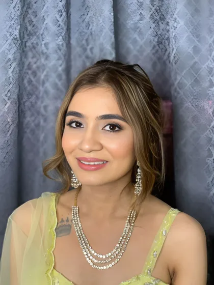 A portrait of Dhriti showing her complete Mehendi look, with soft makeup and an elegant updo.