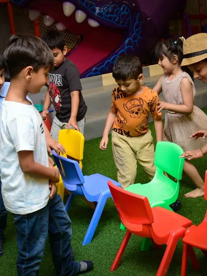 A game of musical chairs is about to begin. The kids circle the colorful chairs, waiting for the music to start.