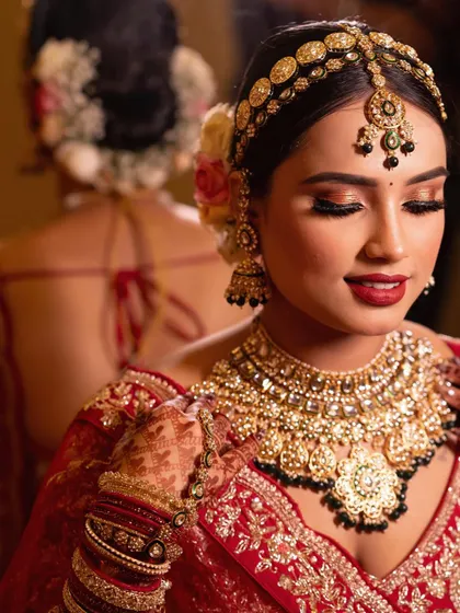 A close-up showcasing the intricate details of the bridal look. The combination of a bold red lip, shimmering gold eyeshadow, and perfectly placed jewelry creates a timeless and regal aesthetic.