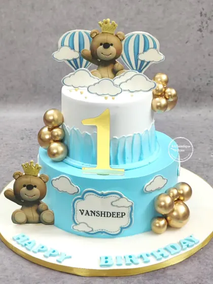 A royal first birthday cake for a little prince. This two-tiered blue and white cake is decorated with teddy bears wearing crowns and floating in hot air balloons.