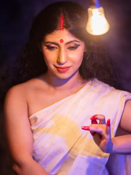 The fully realized goddess, no longer clay but a vessel of divine energy. The single light bulb is a nod to the humble workshops where this magic happens.