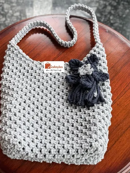 A grey shoulder bag with a contrasting dark grey flower. It's simple, elegant, and perfect for everyday.