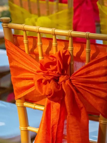 Even the chairs were part of the decor. Here, a bright orange sash is tied into a floral knot on a gold Chiavari chair, adding a pop of color.
