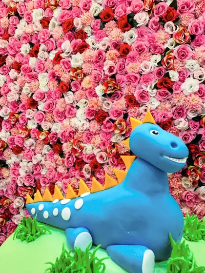 A close-up of the friendly blue dinosaur topper, sculpted from fondant with great detail.