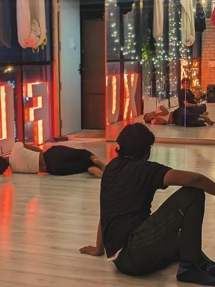 A class in session, with the Flux sign glowing in the background. This space was built for community, art, and transformation.