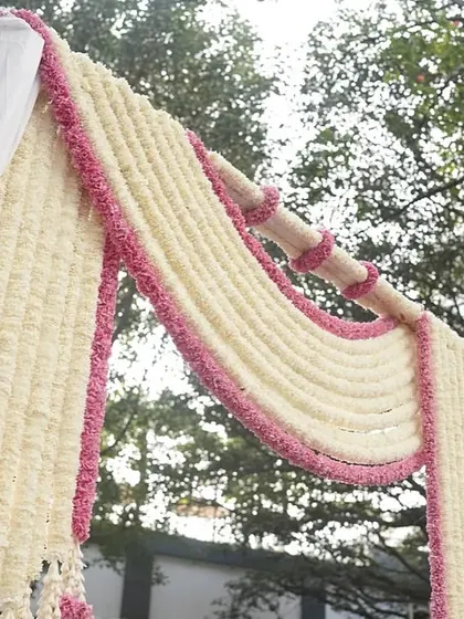 A floral archway made of jasmine and pink flowers, creating a beautiful frame for an entrance or pathway.