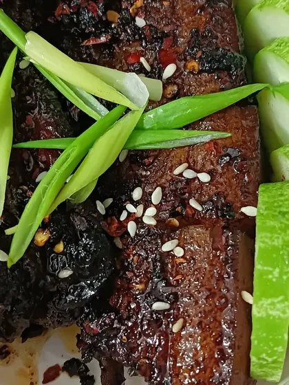 My spicy glazed pork, served with fresh cucumber slices. The pork is coated in a sticky, spicy sauce and sprinkled with sesame seeds and spring onions.