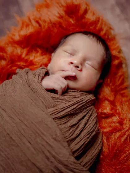 The tiniest details. A simple brown swaddle allows the focus to be on this baby's perfect little hand and peaceful face.