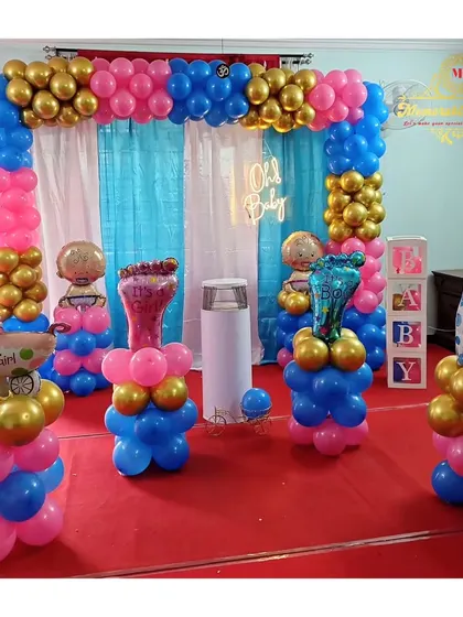 A vibrant baby shower setup with pink, blue, and gold balloons, perfect for a gender reveal party or a general celebration. The decoration includes baby-themed foil balloons and 'BABY' blocks.