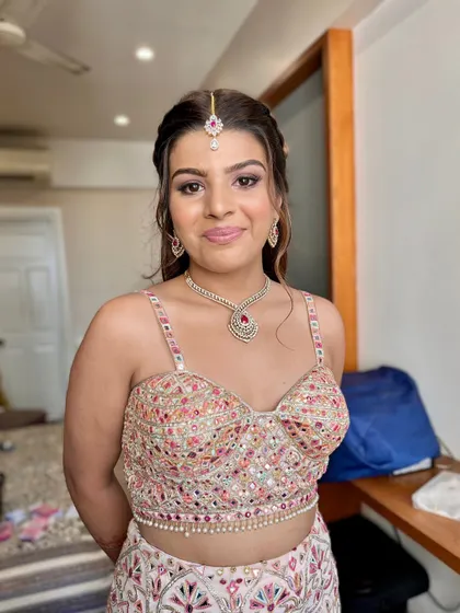 A full-length view of this glamorous and pretty look. The makeup is fresh and radiant, complementing the pastel colors of her outfit.