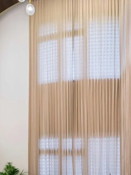 The dramatic, double-height curtains in this living space soften the grand scale of the room while providing privacy. This detail adds a layer of elegance and texture.