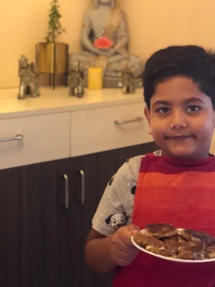 This student proudly holds up his plate of homemade tikkis, showing his accomplishment. These activities are designed to be successful, building a child's confidence.