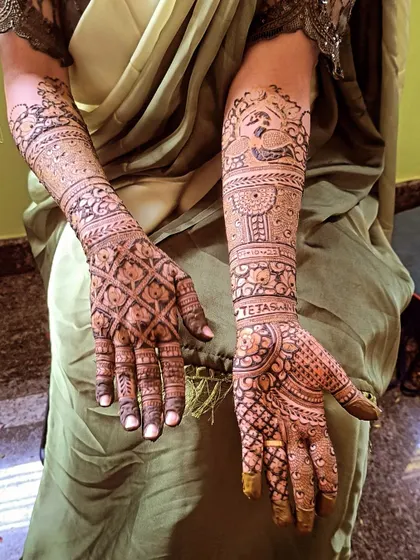 A clear view of a traditional bridal design with peacock figures and the bride's name, 'Tetasha', subtly included in the artwork.