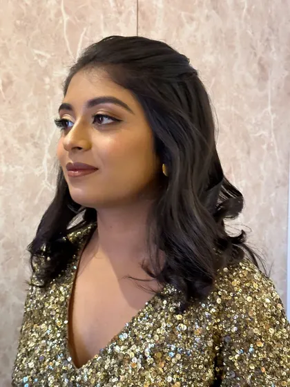 A glamorous party look featuring a gold smokey eye and a glossy nude lip. This style is perfect for an evening event and pairs beautifully with her sequined dress.
