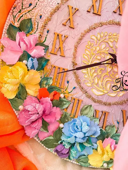 A close-up of a clock with a neutral base and bright flowers. This angle highlights the texture of the sculpted roses and the golden Roman numerals, showing the blend of classic and artistic elements.