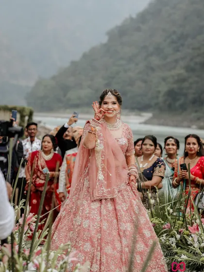 The bride's happy gesture towards her guests as she walks down the aisle, a beautiful candid moment from her destination wedding.