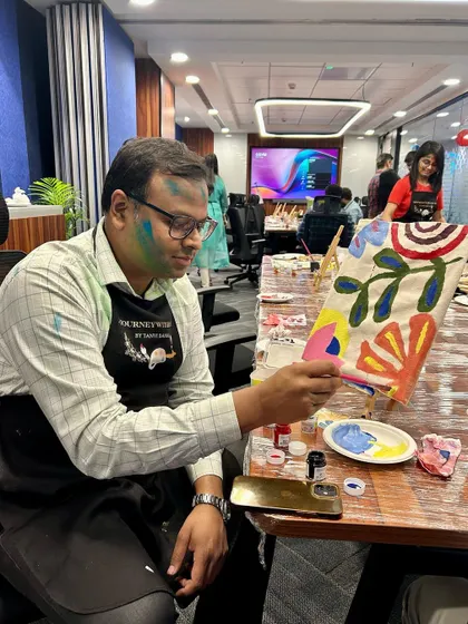A participant proudly showing off his vibrant, abstract tote bag painting. The colors and patterns are so full of energy.