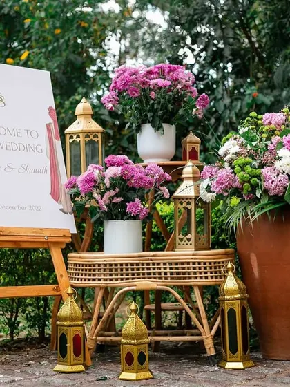 A beautiful welcome setup with a personalized sign, surrounded by purple flowers and traditional brass lanterns, setting a warm and inviting tone.