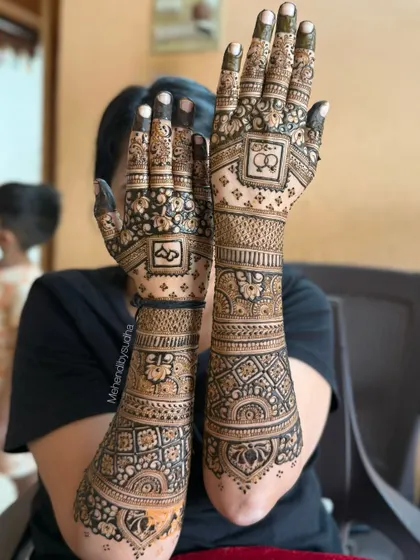 This is a classic full-arm bridal mehendi design, perfect for an engagement or wedding. Notice the fine line work, the balance between the intricate jaal (net) patterns on the palm and the bold floral bands on the forearm, creating a rich and complete look.