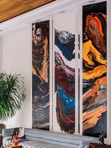 Art can be integrated in unexpected ways. These four vertical panels feature a dynamic, fluid art painting, turning a simple wall into a powerful statement piece that anchors the living area.