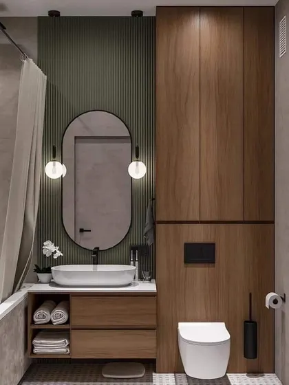 A beautiful combination of textures in this bathroom, with a green fluted wall panel and rich wood cabinets. The round vanity lights add a touch of art deco style.