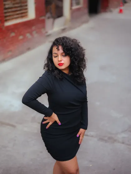 A full-body shot of a model in a black dress, showing her confident stance against a street background. This is a great example of a simple yet powerful urban portrait.