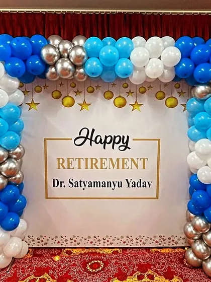 A formal retirement party balloon arch in blue, white, and silver, framing a personalized backdrop for the retiree.