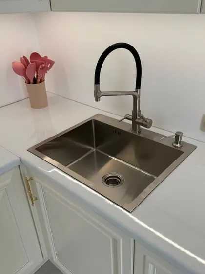 A close-up of the sink area in a classic kitchen, featuring a high-quality stainless steel sink and a modern flexible faucet, all seamlessly fitted into the countertop.