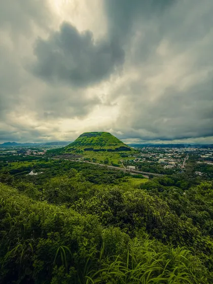 The dramatic landscape of Nashik during the monsoon, with a lush green hill under a stormy sky. The dynamic range on modern phones is incredible for capturing scenes like this.