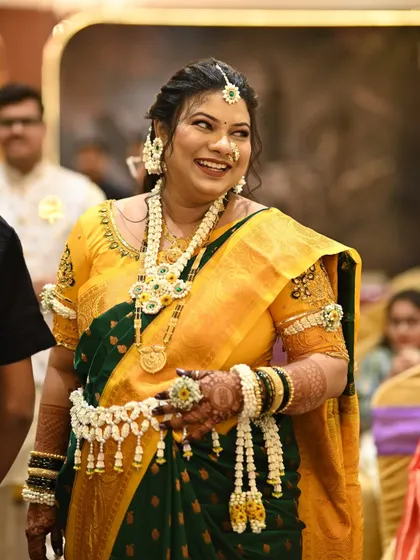 The joy of the occasion is captured in this photo. The client's floral jewellery, made with jasmine buds and yellow flowers, shines as she smiles.