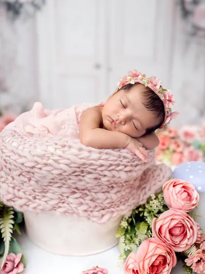 A close-up portrait of the newborn in her floral wonderland. The flower crown and soft textures create a truly enchanting image.