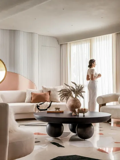 A serene moment in the living room, where a resident enjoys the view. The design is all about creating a tranquil and luxurious atmosphere.